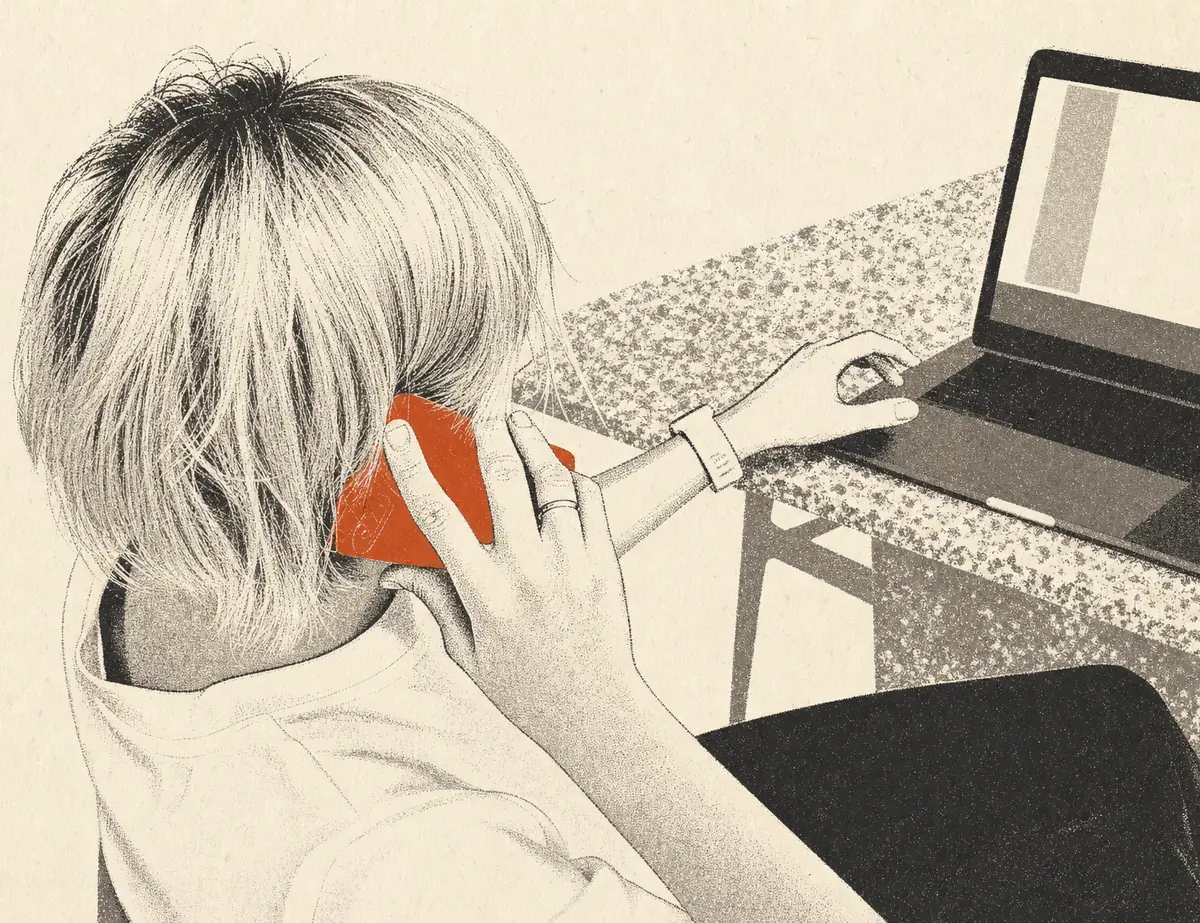 Eine Person von hinten am Schreibtisch, das Telefon am Ohr, vor ihr ein aufgeklappter Laptop