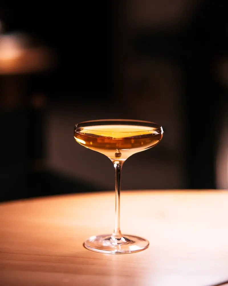 Blasser Drink in einer Coupe auf dem Holztisch