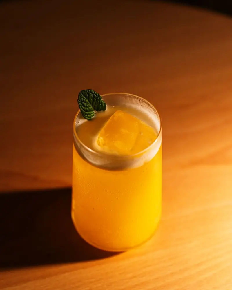 Hellgelber Drink mit Minzblatt im Glas auf dem Holztisch