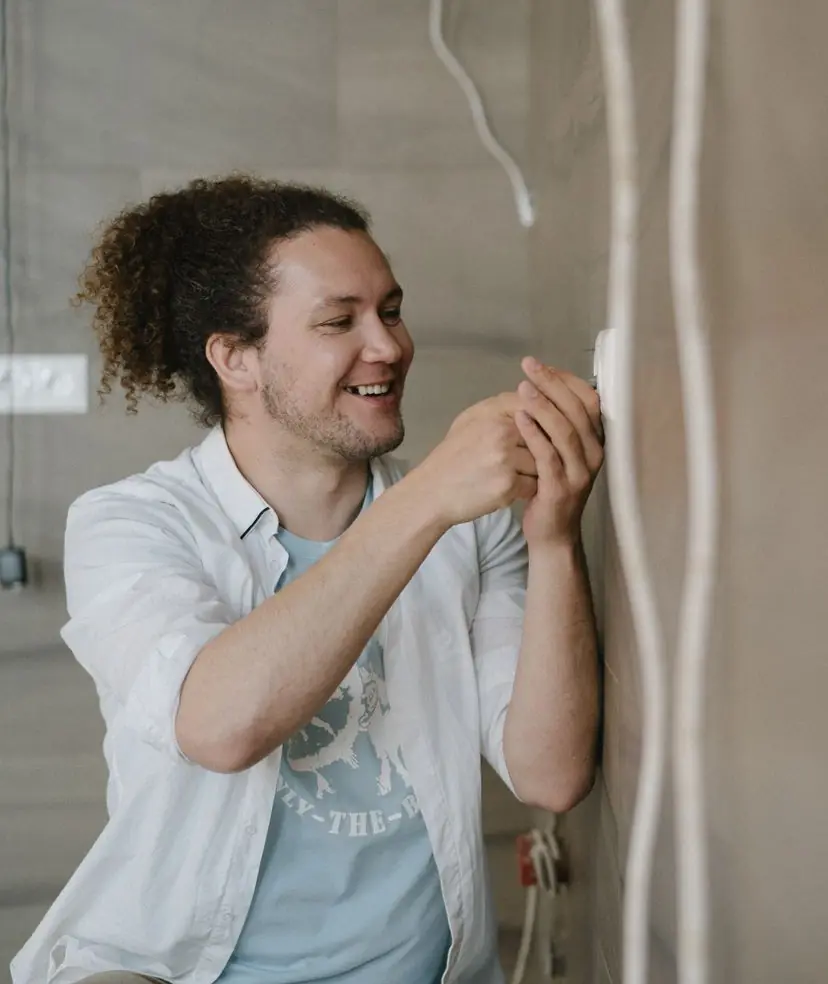 Jonas, Elektrotechnikermeister, montiert lachend eine Unterputzdose an einer Wand.