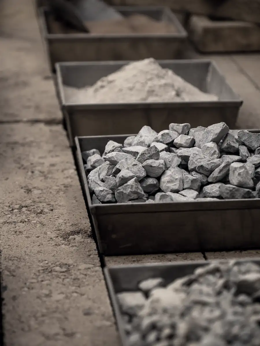 Proben von gebrochenem Material in Metallschalen, vom feinen Sand bis zum groben Splitt