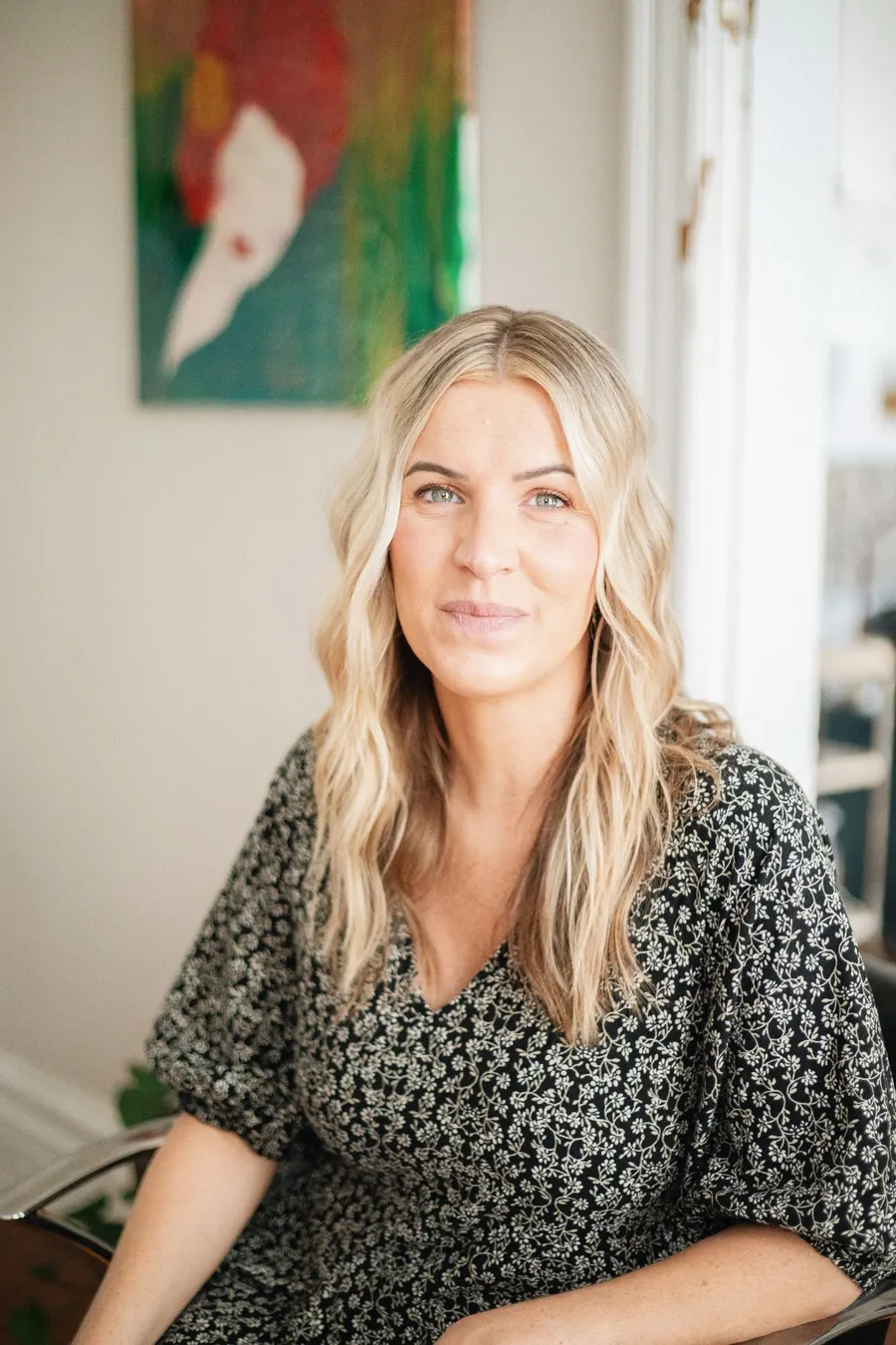 Juli Brandstetter, Inhaberin von SCHERE, im Salon, langes, gewelltes blondes Haar, Blick in die Kamera.