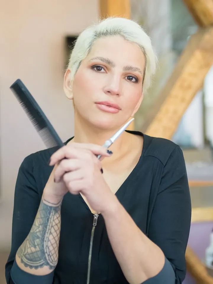 Mira Enzinger im Salon, platinblondes Kurzhaar, Kamm und Farbpinsel in der Hand.