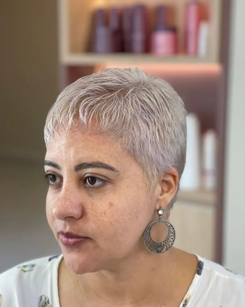 Frau mit kurzem, silbergrauem Haar und großen Ohrringen.