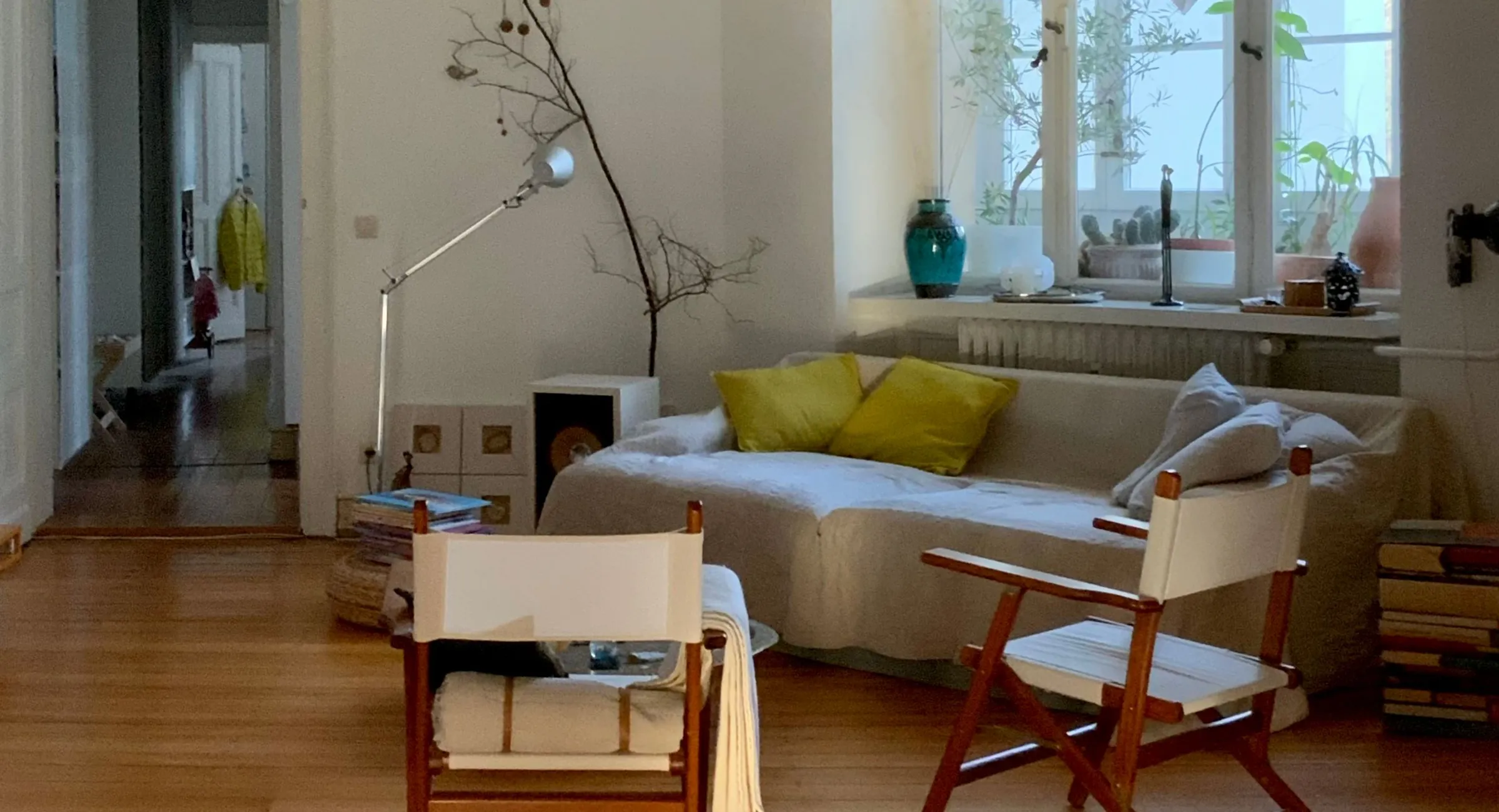 Helles Wohnzimmer einer Altbauwohnung mit großen Fenstern und Parkettboden.