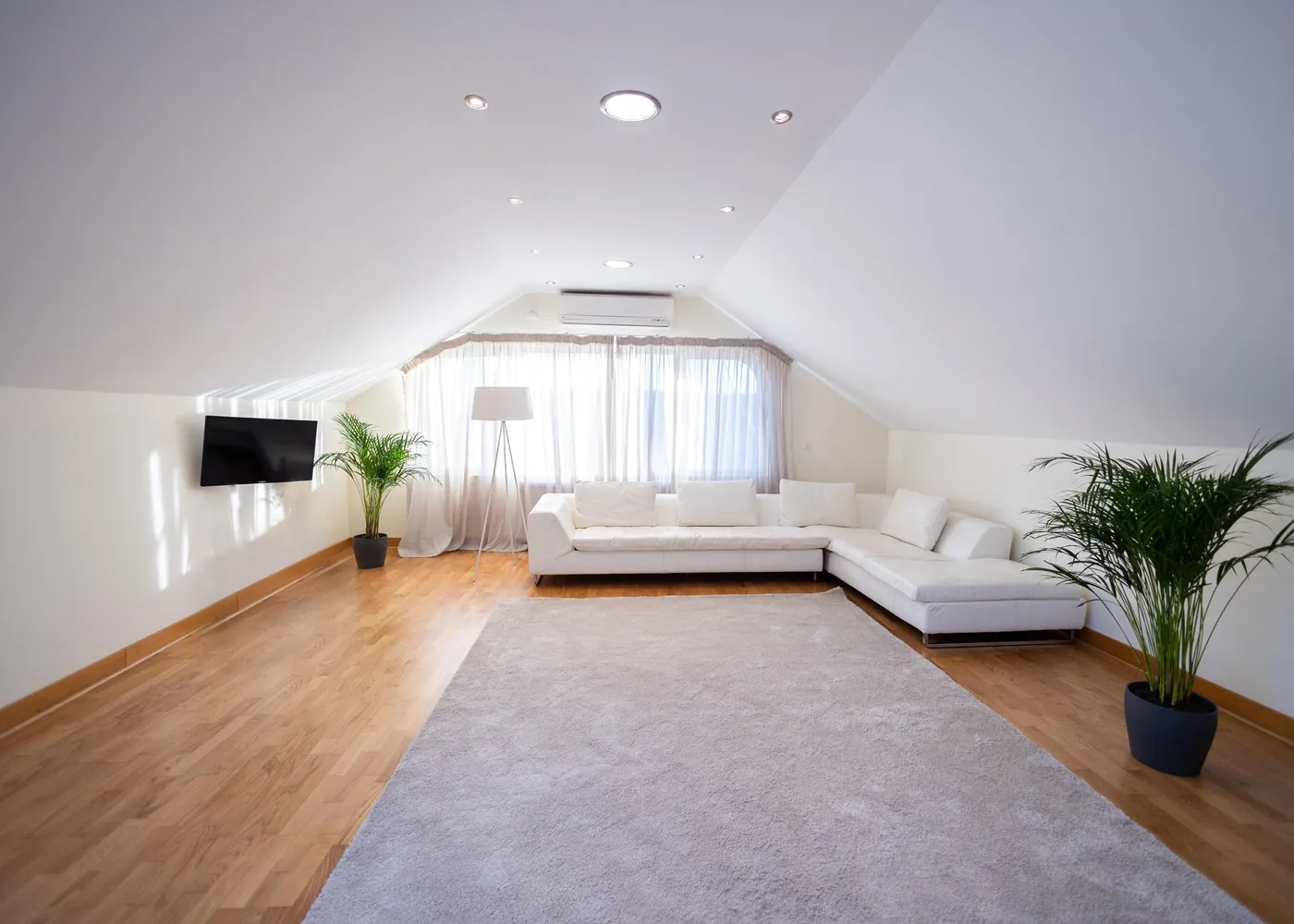 Heller Dachgeschossraum mit schräger Decke und Holzboden.