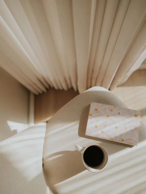 Tasse und Notizbuch auf einem Stuhl, von oben