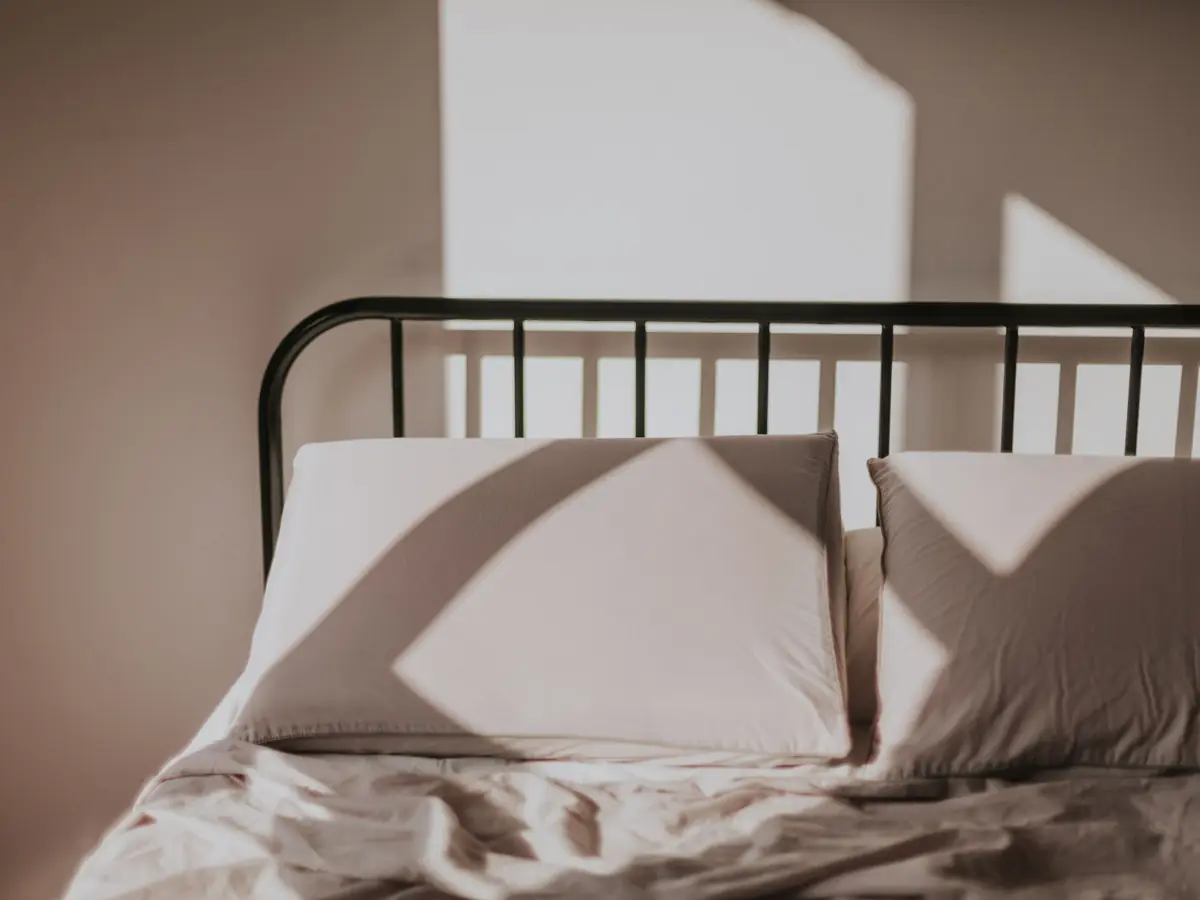 Morgensonne zeichnet Fensterschatten auf Bett und Wand
