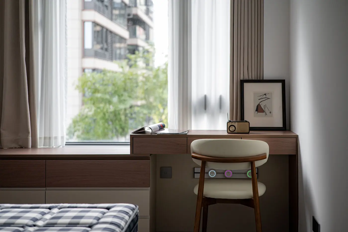 Arbeitsecke mit Holzschreibtisch, Stuhl und Leuchte vor einem Fenster mit Vorhang