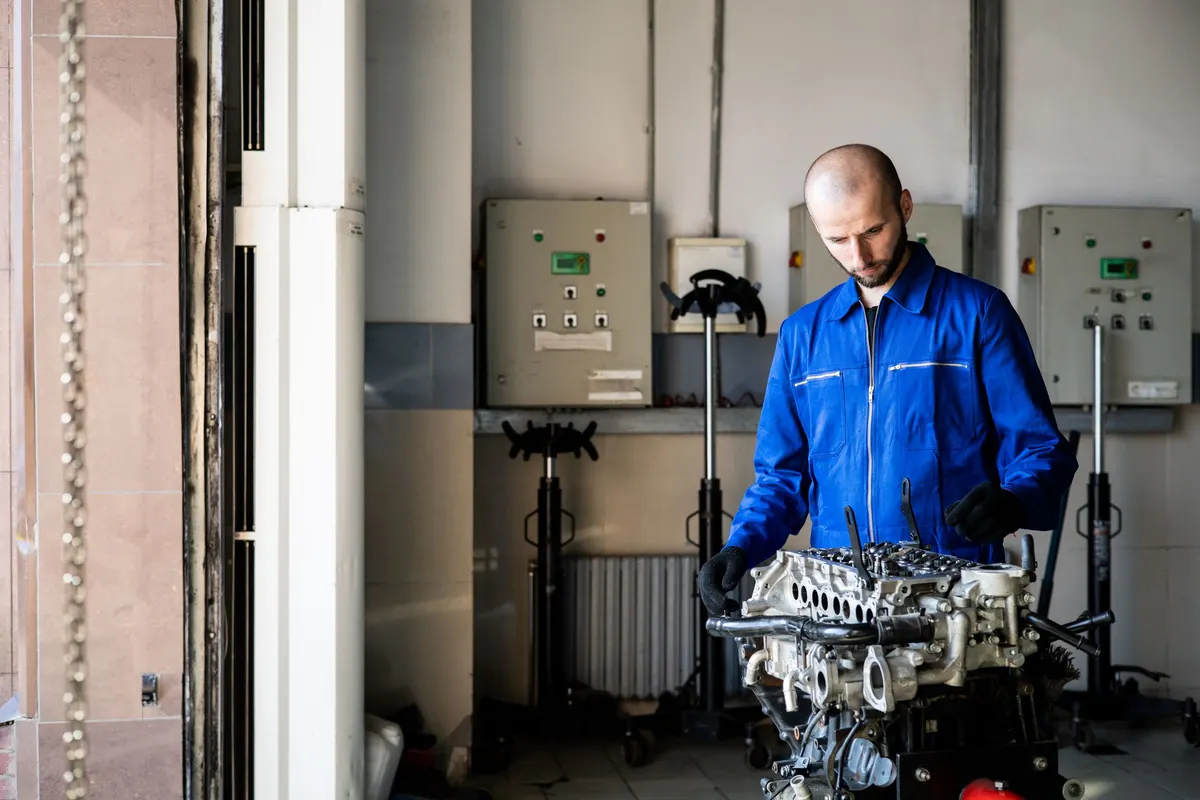 Techniker arbeitet an einem ausgebauten Motorblock.