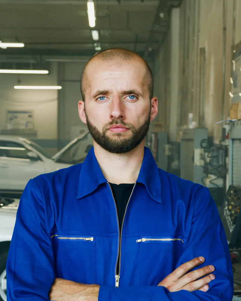 Porträt des Werkstattleiters in blauem Arbeitsanzug.