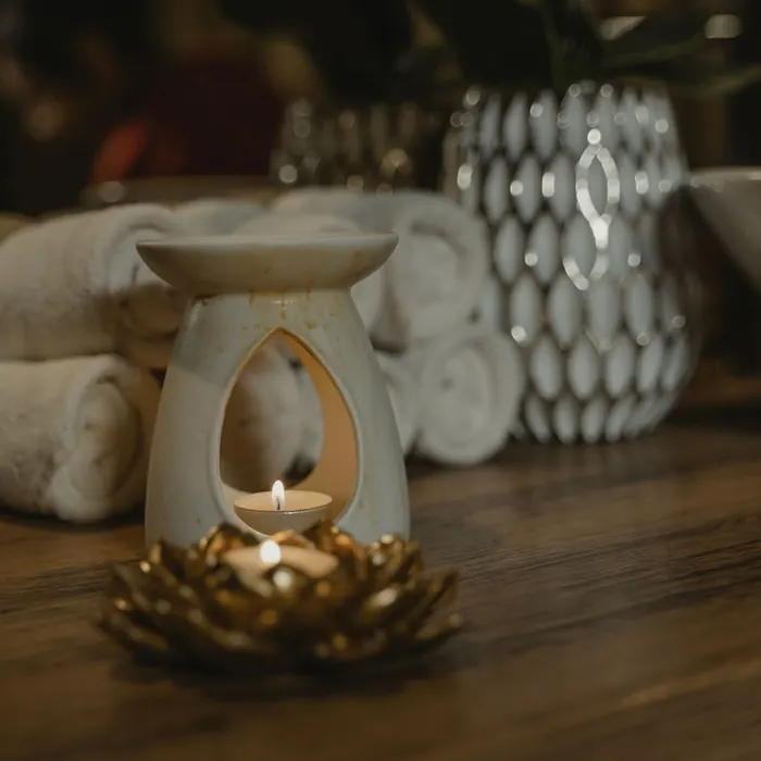 Duftlampe mit brennendem Teelicht vor gerollten Handtüchern.
